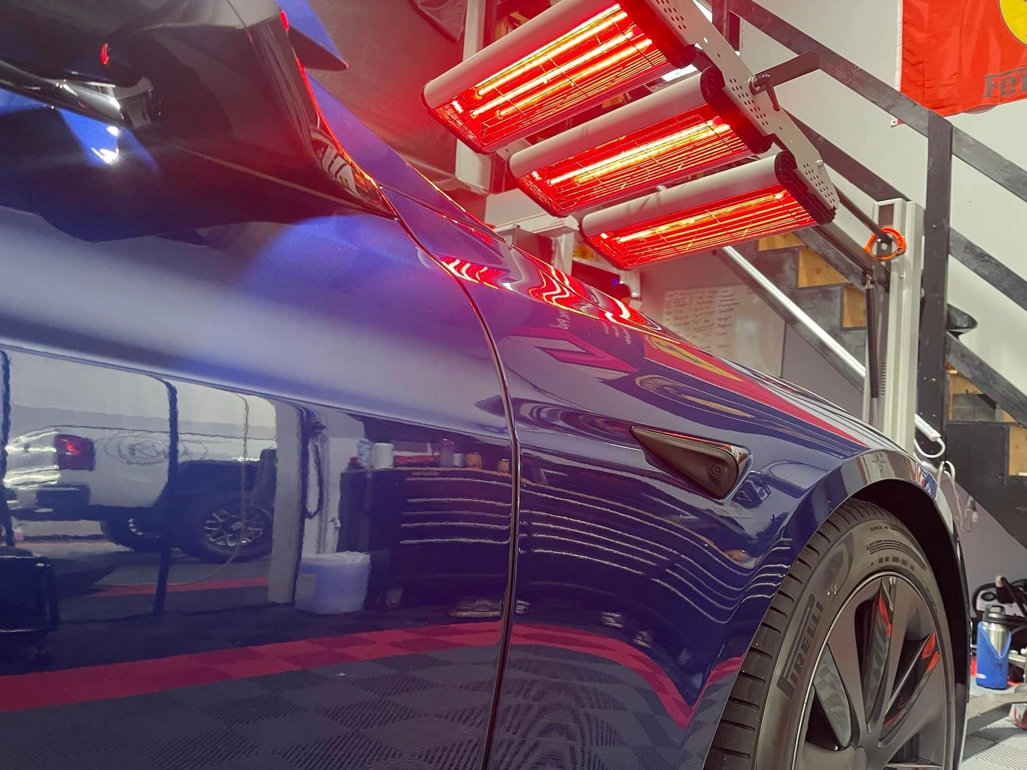 Blue Tesla under ceramic coating heat lamps
